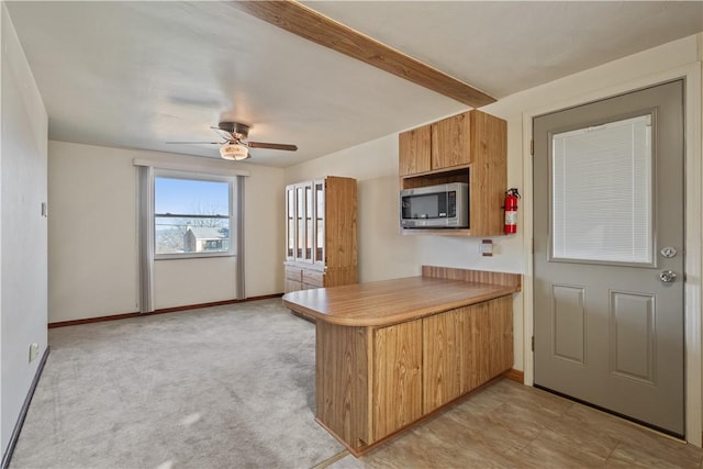 kitchen featuring stainless steel microwave, baseboards, a peninsula, light countertops, and a ceiling fan