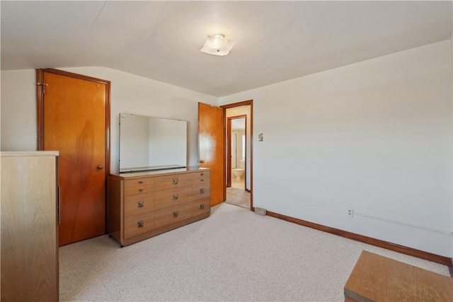 bedroom with light colored carpet, baseboards, and vaulted ceiling