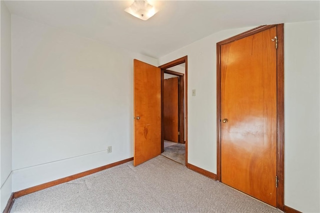 unfurnished bedroom featuring baseboards and light colored carpet