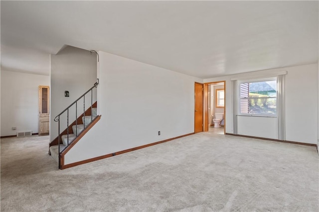 spare room featuring visible vents, baseboards, stairway, and carpet