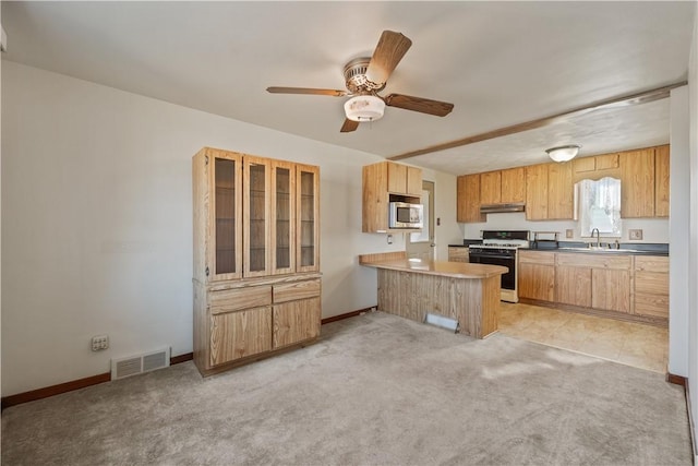 kitchen featuring a peninsula, visible vents, under cabinet range hood, stainless steel microwave, and range with gas cooktop