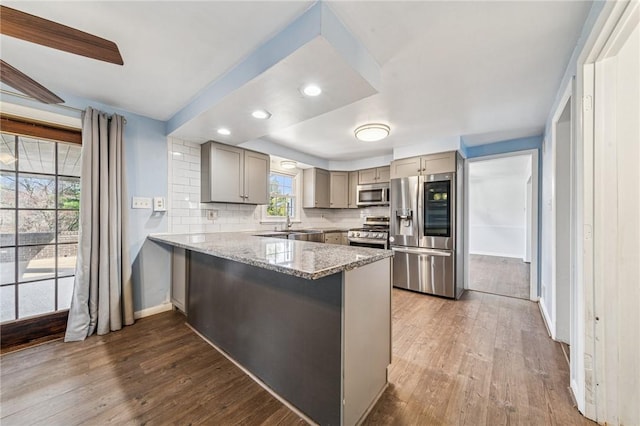 2096 Ramsey Rd, Monroeville, PA 15146 - kitchen featuring light stone counters, a peninsula, gray cabinetry, dark wood-type flooring, and appliances with stainless steel finishes