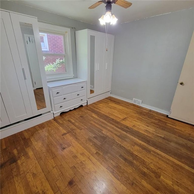 unfurnished bedroom featuring baseboards, wood-type flooring, a ceiling fan, and visible vents
