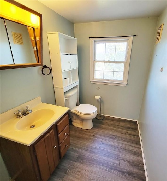 half bathroom with vanity, baseboards, toilet, and wood finished floors