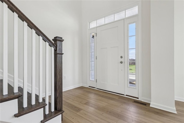 foyer with stairway, light wood-style floors, and a wealth of natural light