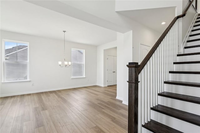 stairs featuring an inviting chandelier, baseboards, and wood finished floors
