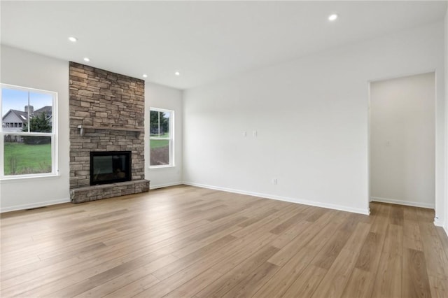 unfurnished living room with recessed lighting, baseboards, a fireplace, and light wood-type flooring