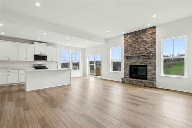 unfurnished living room with light wood-type flooring, a sink, a fireplace, and recessed lighting