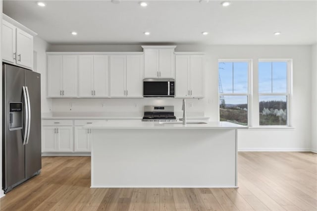 kitchen featuring light countertops, an island with sink, white cabinets, and stainless steel appliances