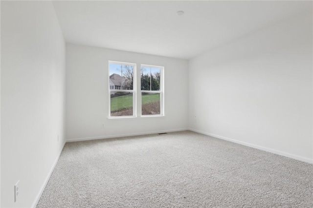 carpeted empty room featuring baseboards and visible vents