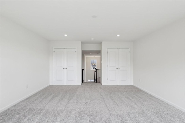 unfurnished bedroom with baseboards, recessed lighting, carpet floors, and two closets