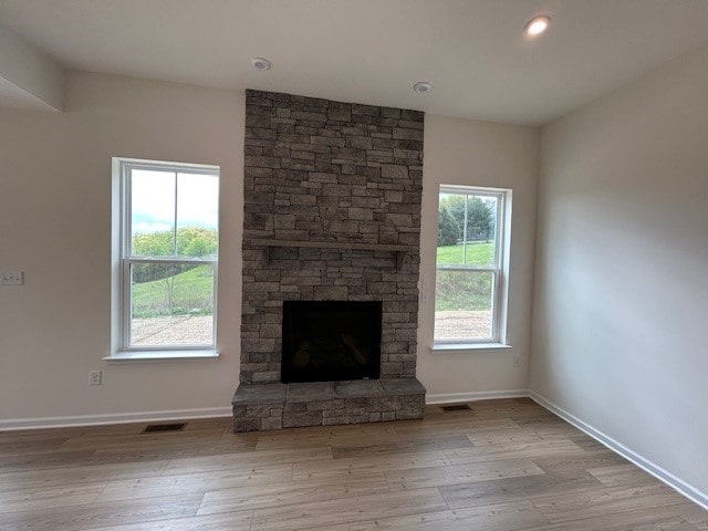 unfurnished living room featuring baseboards, a fireplace, wood finished floors, and visible vents