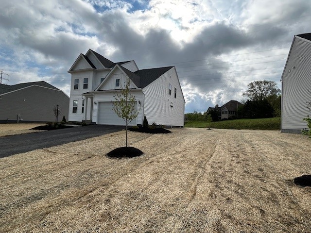 view of property exterior with board and batten siding, a garage, and aphalt driveway