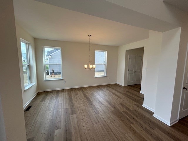 unfurnished dining area with baseboards, dark wood-style floors, and a chandelier