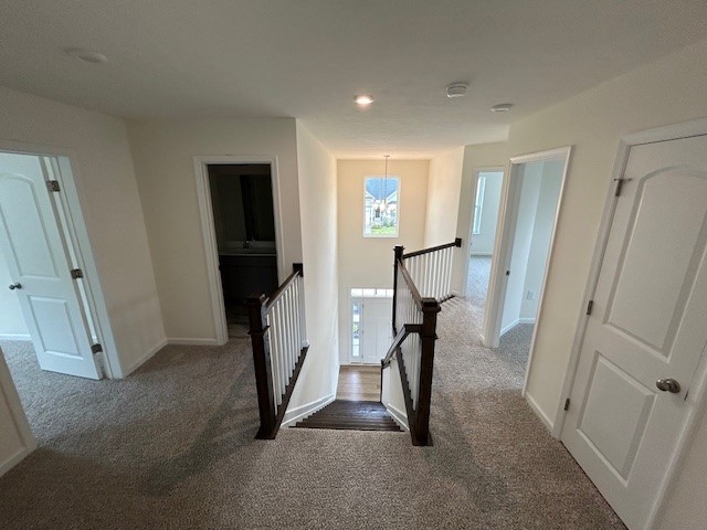 interior space featuring baseboards, recessed lighting, carpet, and an upstairs landing