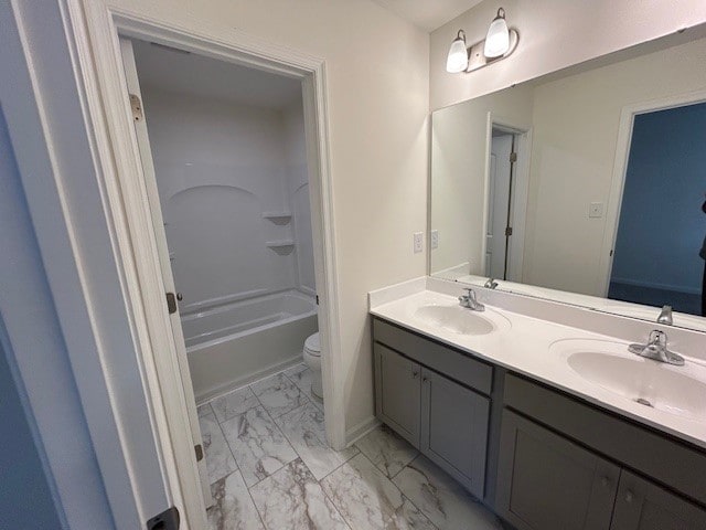 bathroom featuring double vanity, toilet, a sink, and marble finish floor