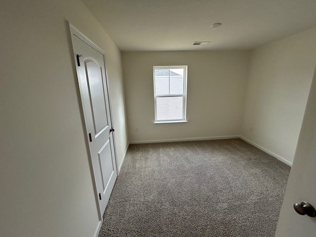 carpeted spare room featuring baseboards and visible vents