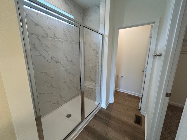 full bath with baseboards, visible vents, a shower stall, and wood finished floors