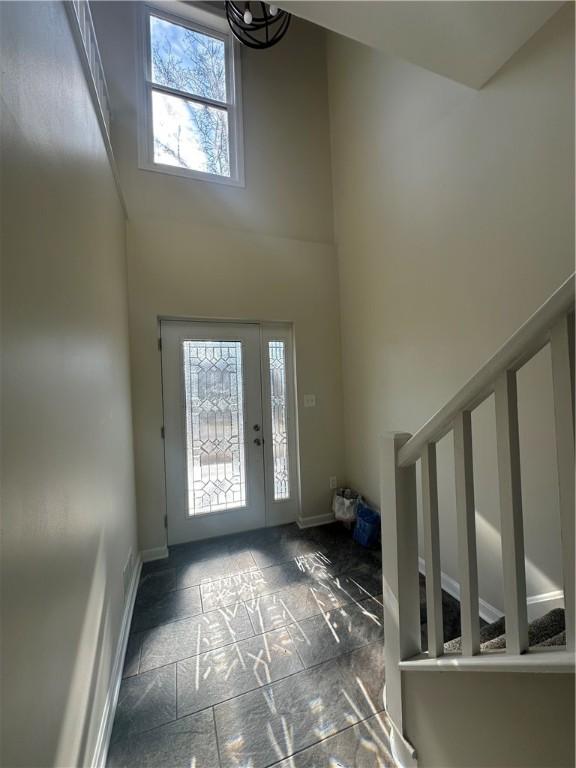 entrance foyer with baseboards and a towering ceiling