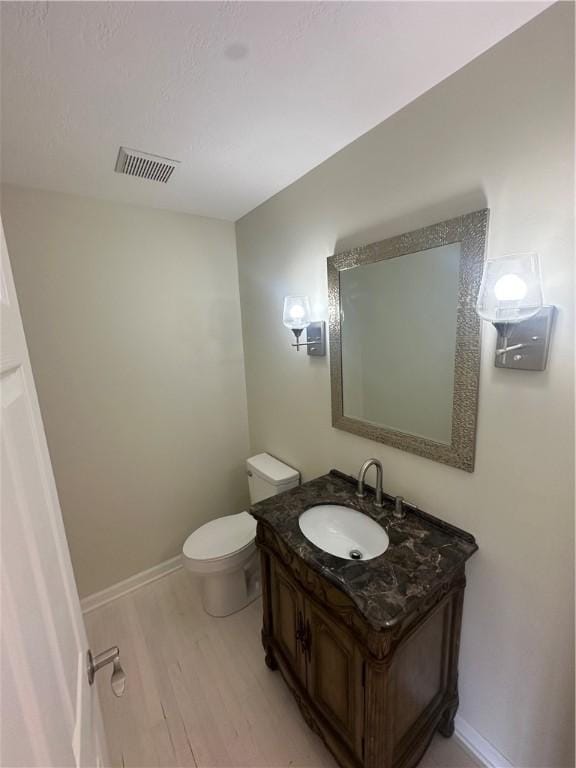 bathroom featuring vanity, baseboards, toilet, visible vents, and wood finished floors