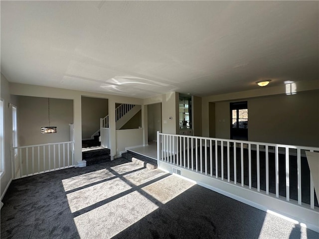 spare room featuring stairway and carpet flooring