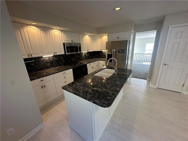 kitchen with dark stone counters, tasteful backsplash, recessed lighting, a sink, and stainless steel appliances