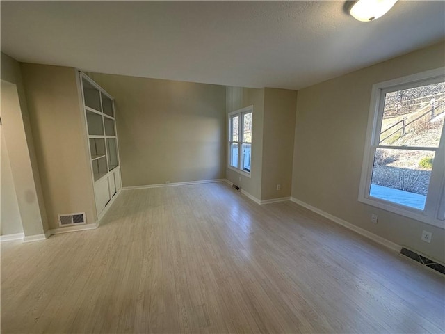 unfurnished room with visible vents, baseboards, and wood finished floors