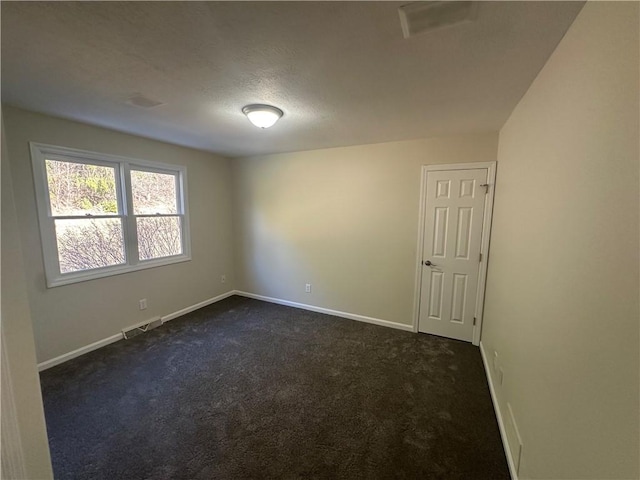 empty room with visible vents, baseboards, dark colored carpet, and a textured ceiling