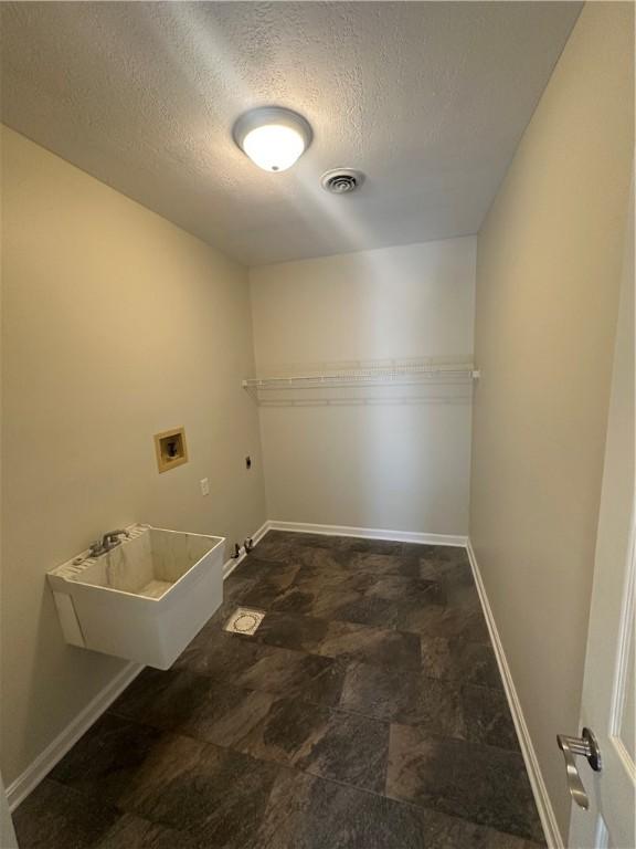 washroom featuring laundry area, electric dryer hookup, a textured ceiling, visible vents, and washer hookup