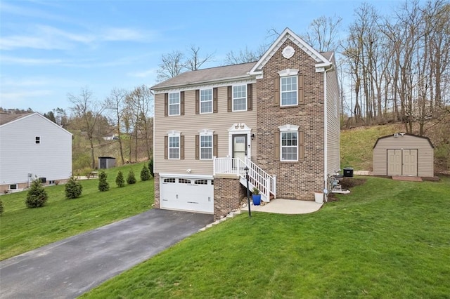 view of front of home featuring driveway, a front yard, a storage shed, an outbuilding, and a garage