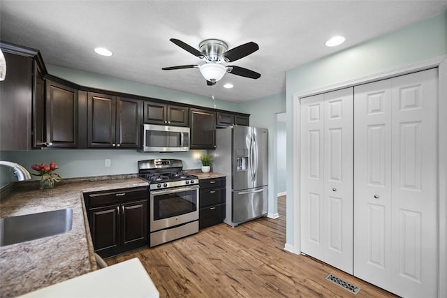 kitchen featuring dark brown cabinetry, light wood-type flooring, a ceiling fan, stainless steel appliances, and a sink