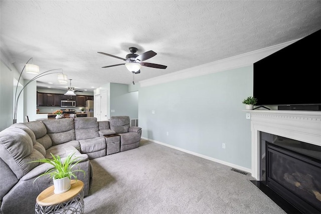 carpeted living area with visible vents, baseboards, a ceiling fan, a textured ceiling, and a fireplace with flush hearth