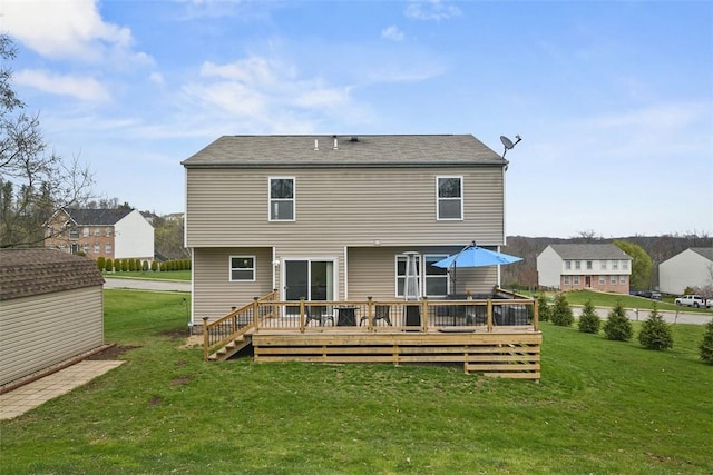 rear view of house featuring an outdoor structure, a deck, and a lawn