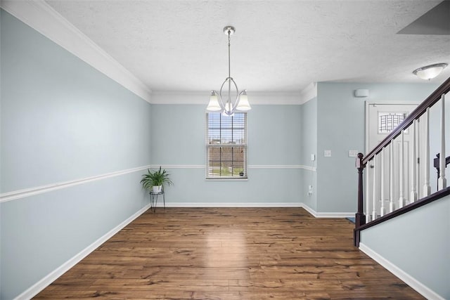 unfurnished dining area featuring a textured ceiling, stairway, a chandelier, wood finished floors, and baseboards