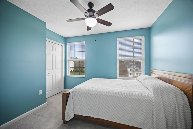 bedroom with ceiling fan, a textured ceiling, a closet, carpet flooring, and baseboards