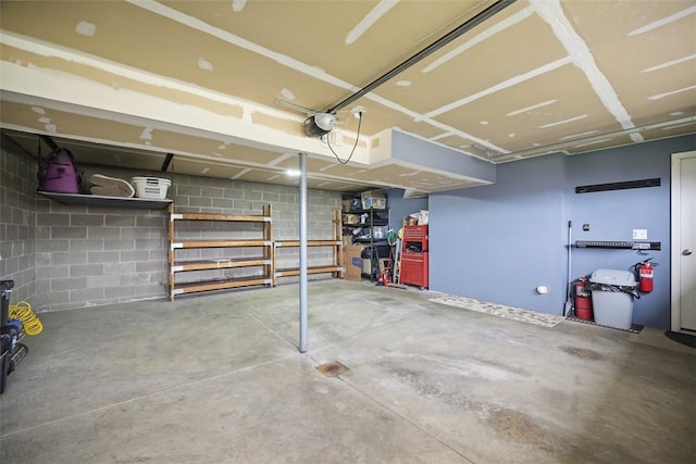garage featuring concrete block wall and a garage door opener