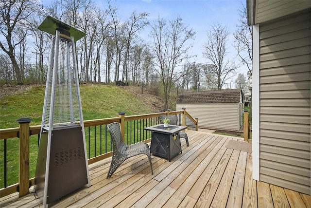 wooden terrace featuring a storage unit, an outdoor structure, and a lawn