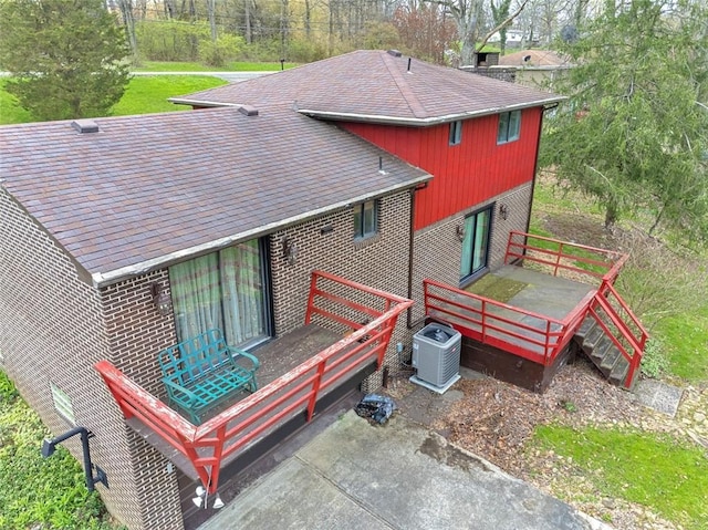 back of house with central air condition unit, a wooden deck, and brick siding