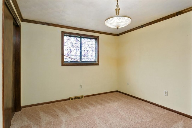 empty room featuring visible vents, light colored carpet, baseboards, and ornamental molding