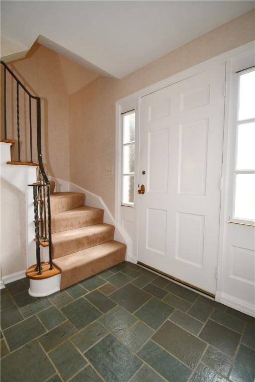 foyer featuring stairway, stone finish floor, and baseboards