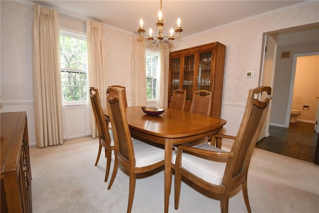 dining room featuring ornamental molding, light colored carpet, a notable chandelier, and baseboards