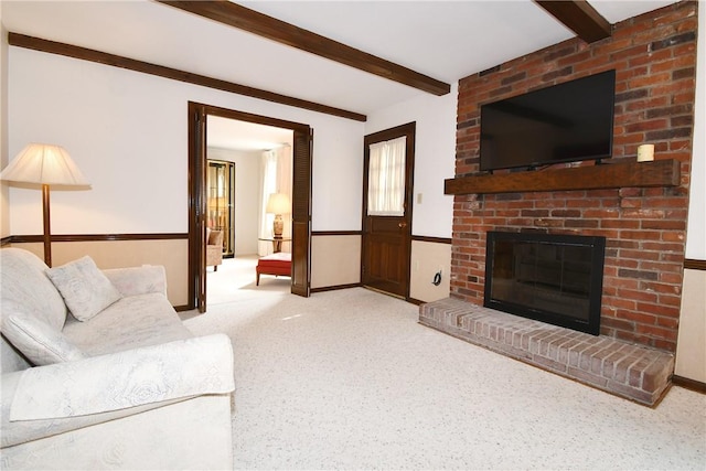 carpeted living area with a fireplace and beam ceiling
