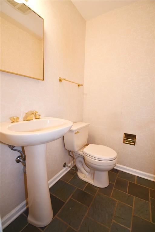 half bath with visible vents, baseboards, and toilet