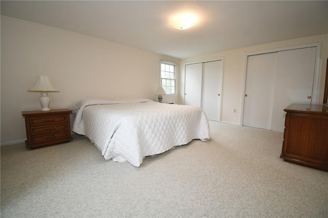 bedroom with two closets, carpet flooring, and baseboards