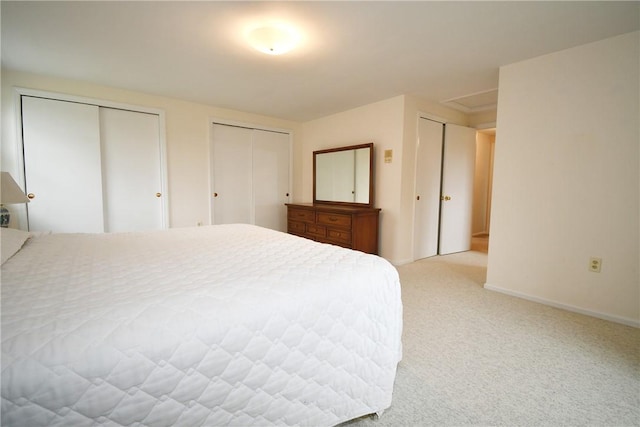 bedroom with two closets, carpet flooring, and baseboards