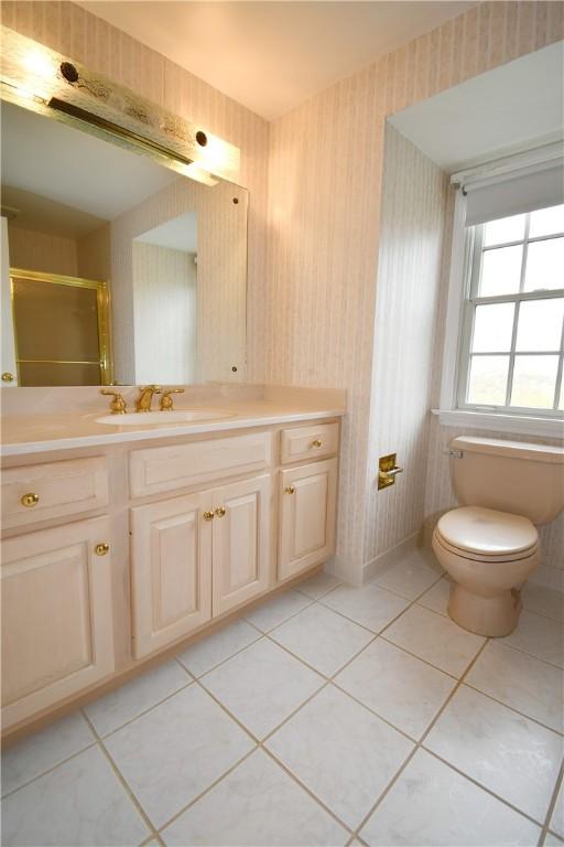 full bath featuring vanity, wallpapered walls, tile patterned floors, toilet, and a shower with shower door