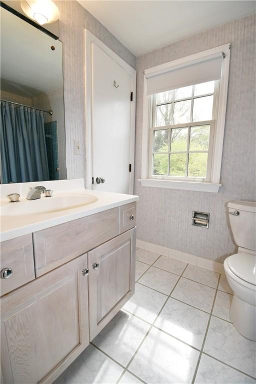 full bath with vanity, baseboards, wallpapered walls, tile patterned flooring, and toilet