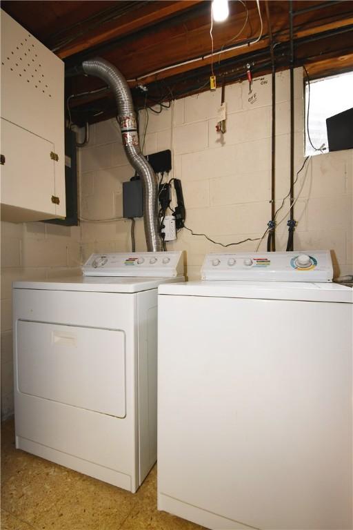 washroom featuring cabinet space, concrete block wall, and washing machine and dryer