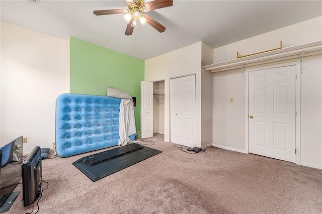 exercise area with carpet floors, ceiling fan, and baseboards