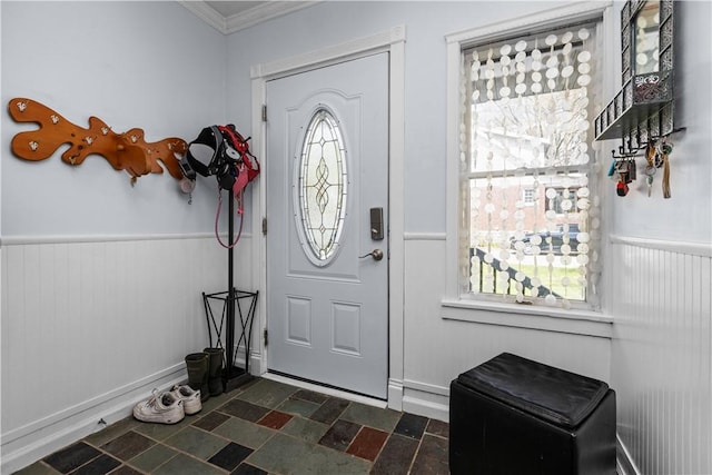 foyer entrance featuring ornamental molding, wainscoting, and stone finish flooring